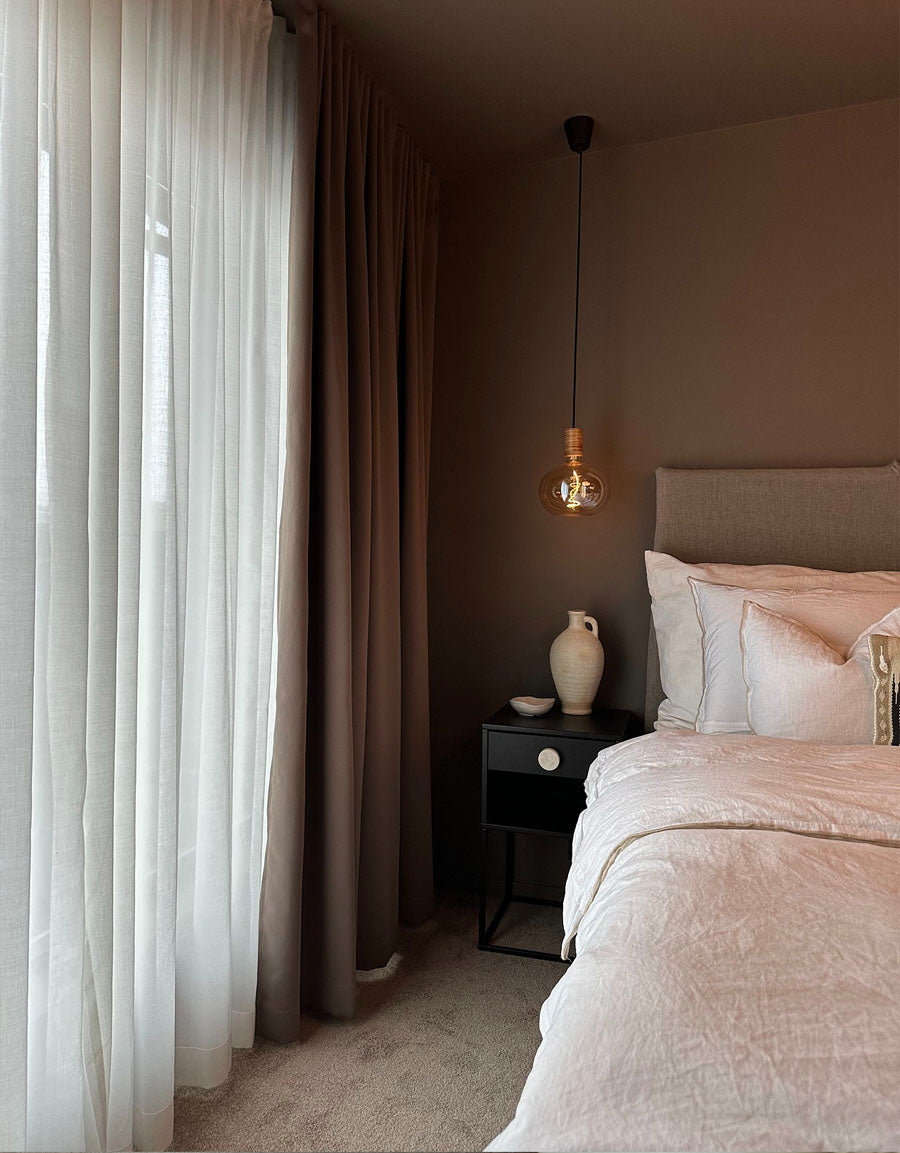 Hotellgardiner i brunt och vitt i ett mörkt sovrum