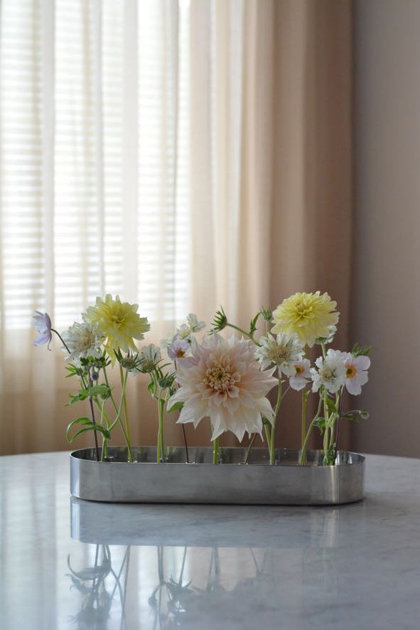 Blommor på matbord med beiga gardiner i bakgrunden