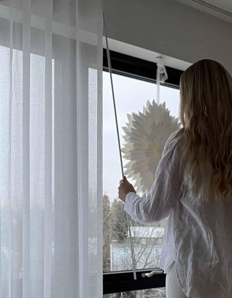 Kvinna som drar i en dragstav fäst i en gardin