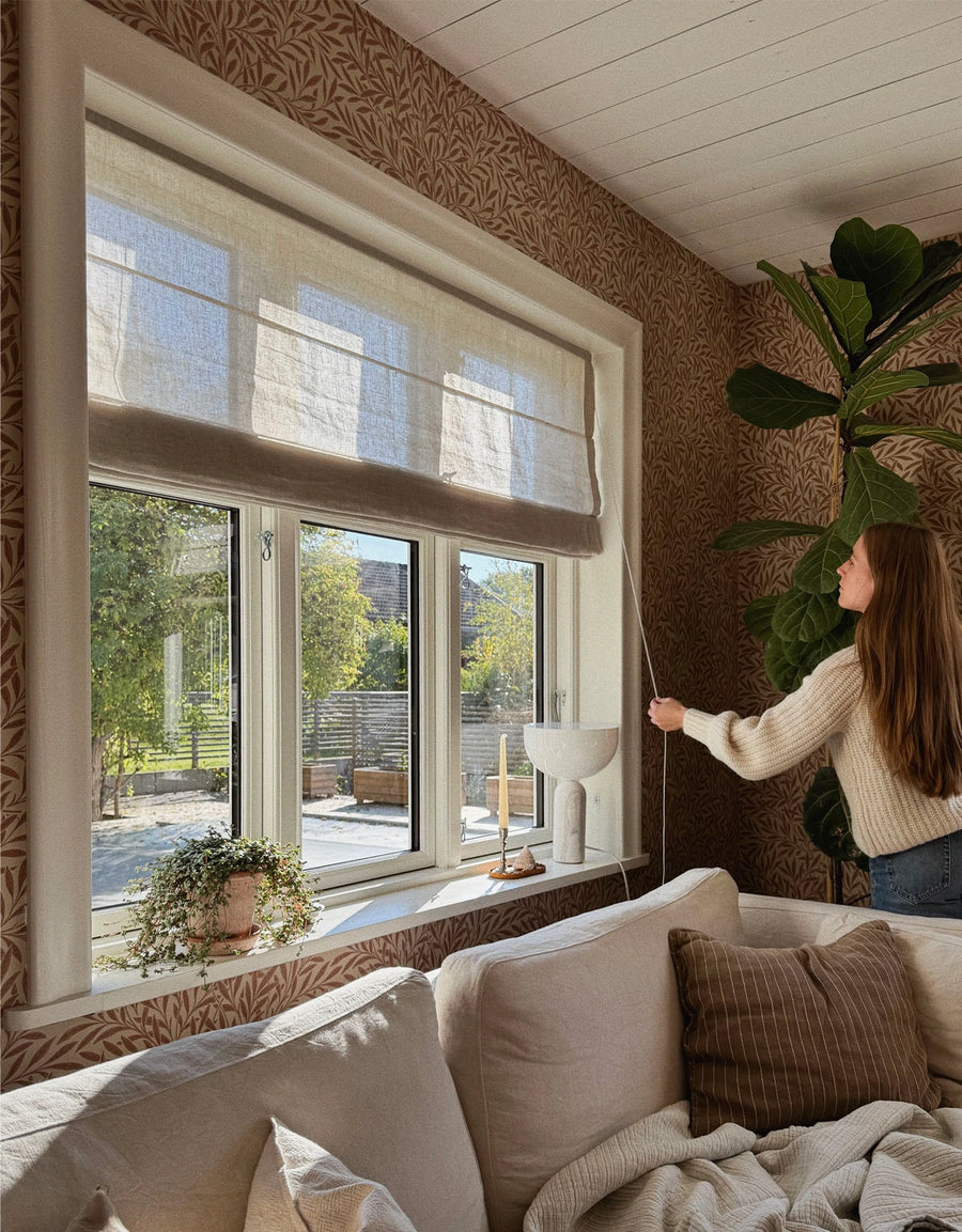 Kvinna justerar en beige hissgardin